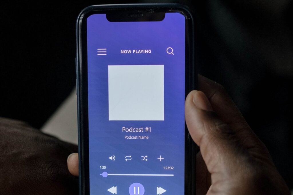 Mano sosteniendo un celular que reproduce un episodio de podcast